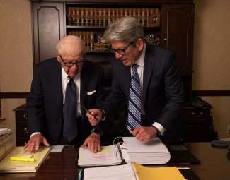 Stu and Leonard Finz reviewing legal paperwork in their Long Island personal injury law office