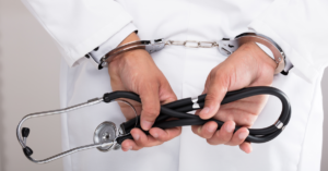 doctors hand handcuff holding stethoscope behind