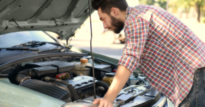 young man looking under car