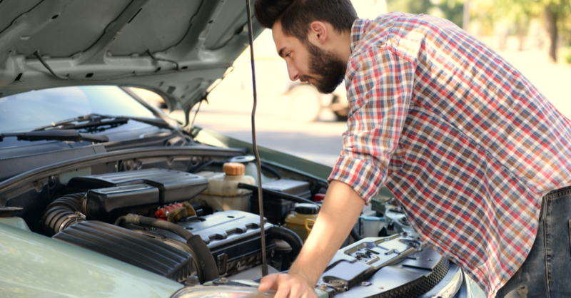 young man looking under car