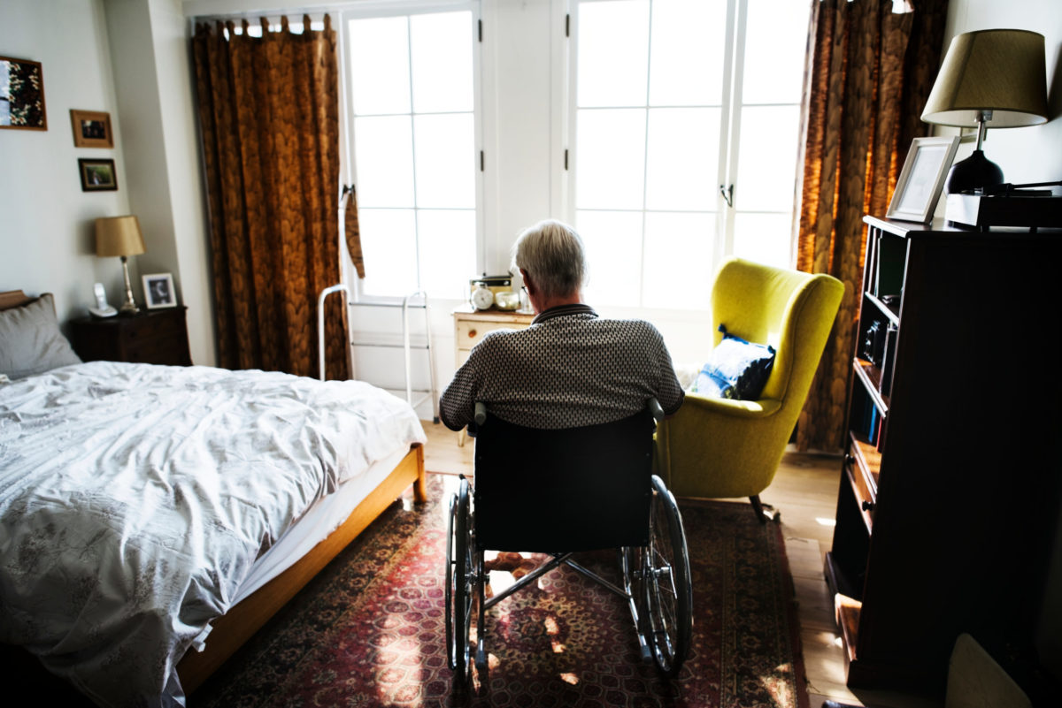elderly man sitting alone in a New York nursing home room