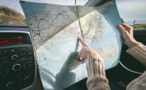 New York woman pointing to road trip destination on map