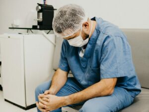 doctor looking down, fatigued after a long shift in NY hospital