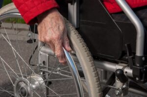 Old Lady's hand on wheel chair tire.