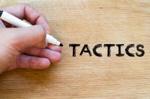 Human hand over wooden background and tactics text concept