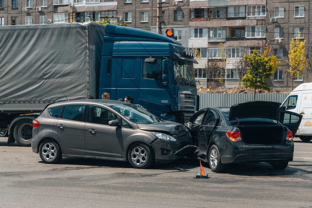 A serious truck and car collision at a Brooklyn intersection with visible front-end damage and emergency responders nearby.