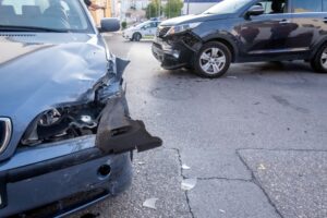 Two damaged cars at an intersection after a collision, with debris scattered on the roadway.