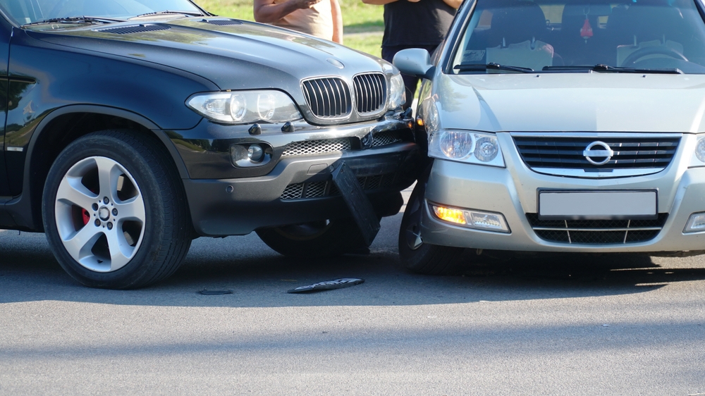 Two vehicles with front-end damage after a collision on a roadway.