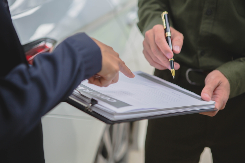 Insurance or legal representative reviewing car accident claim paperwork with an injured driver