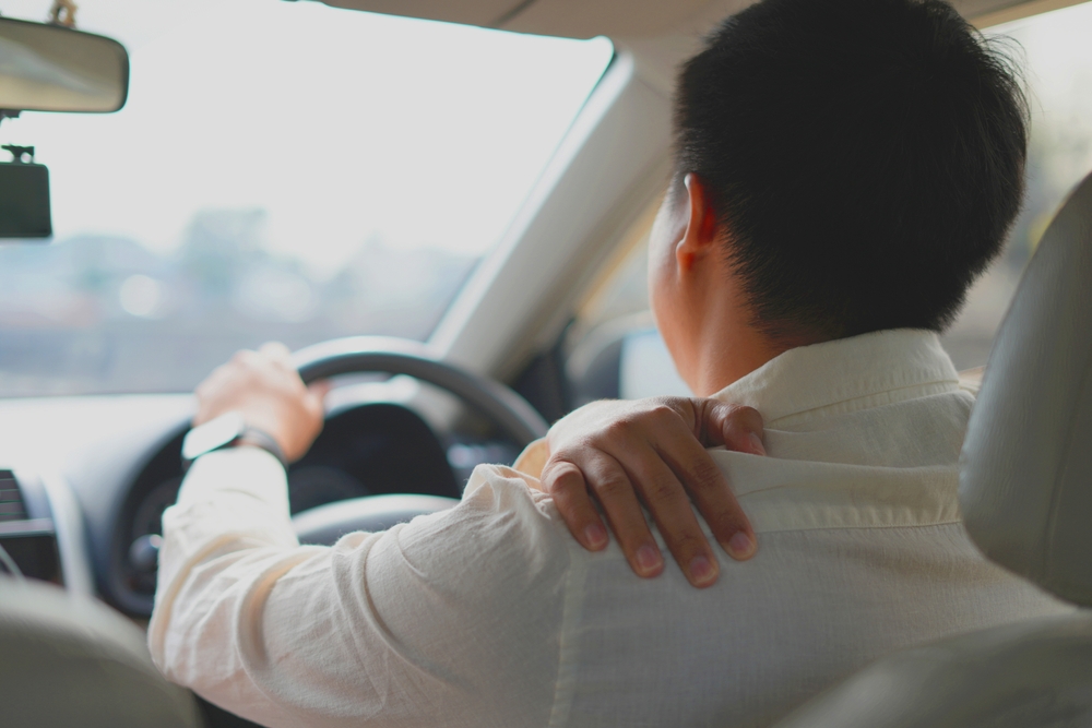 Driver holding neck in pain after a car accident, showing symptoms of cervical spine injury