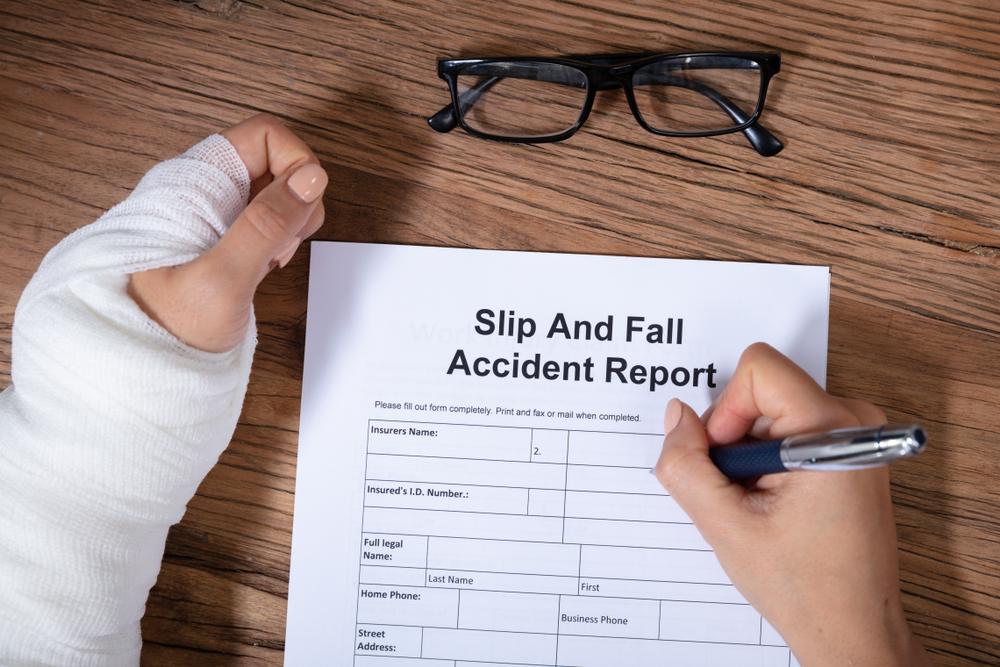 Injured person filling out a slip and fall accident report after getting hurt on unsafe property in Brooklyn.