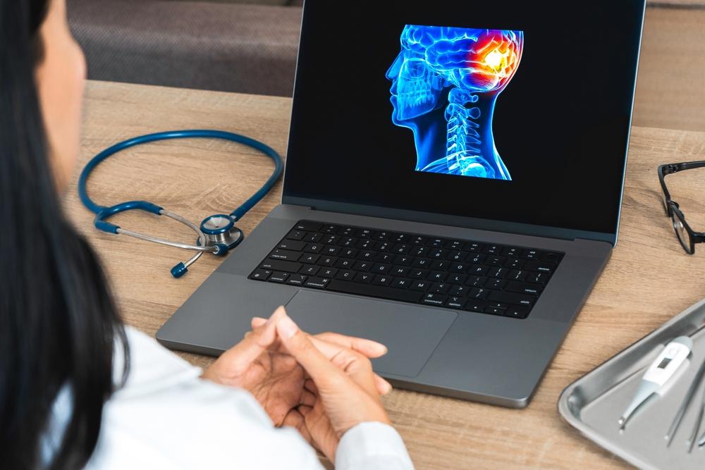 Doctor reviewing digital brain injury scan on laptop during traumatic brain injury evaluation